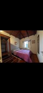 a bedroom with a bed with a purple blanket at CHALET económico cerca del Mar in Costa Azul