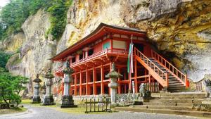 a red building in a mountain with stairs in front at Renovated room! Japanese inn Matsumoto in Ichinoseki