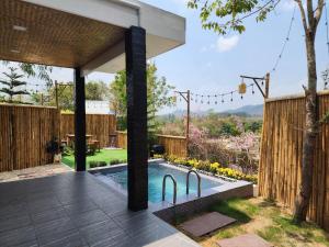 a backyard with a swimming pool and a wooden fence at Phunapat camping Pool villa in Ban Nong Chaeng