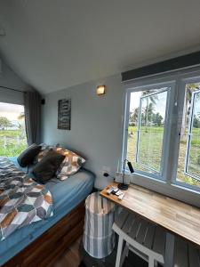 a bedroom with a bed and a desk and windows at Beachfront Tiny House - Eden Pod with FREE Rowboat in Nathon Bay