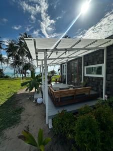 a house with a deck with a pergola at Beachfront Tiny House - Eden Pod with FREE Rowboat in Nathon Bay