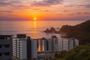a sunset over the ocean with a group of buildings at Seaview Turtle Cove in Kampong Bugis