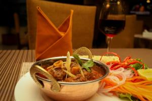 a bowl of food on a table with a glass of wine at Yatri Suites and Spa in Kathmandu
