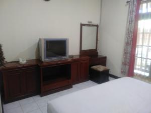a bedroom with a television on a dresser with a mirror at De Gadri Ndalem Yogyakarta in Bantul