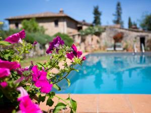 una piscina con flores púrpuras frente a una casa en Novelleto, en Monteriggioni