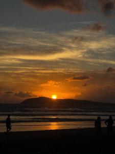 a group of people walking on the beach at sunset at The Stoked Hideout - Bagasbas Beach in Daet +3 photos