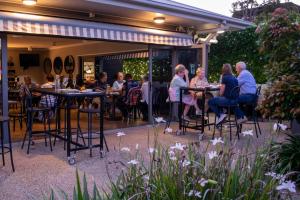 a group of people sitting at tables in a garden at Potters Toowoomba Hotel in Toowoomba