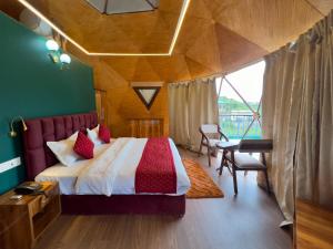 a bedroom with a bed and a desk and a window at The host in Kanatal