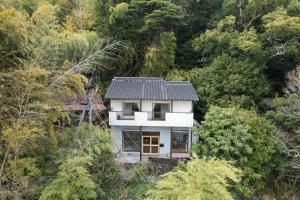 a small white house in the middle of a forest at CLIP INN by RITO 坂の上の一棟貸し in Tsushima