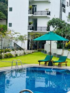 a swimming pool with an umbrella and two chairs and a table and an umbrella at O2 Resort Welimada in Nugatalawa +21 photos