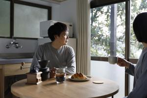 a man sitting at a table with a plate of food at CLIP INN by RITO 坂の上の一棟貸し in Tsushima