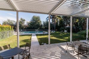 a patio with tables and chairs and a swimming pool at Sicilia's Art Hotel & Spa in Acitrezza