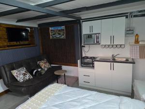 a bedroom with a bed and a kitchen with a couch at CLP Lodge in Bela-Bela