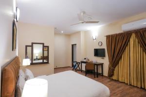 a hotel room with a bed and a desk with a television at Hotel One Bahawalpur in Bahawalpur
