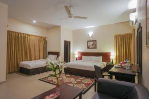 a hotel room with two beds and a table at Hotel One Bahawalpur in Bahawalpur +35 photos