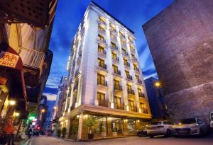 een hoog wit gebouw in een stadsstraat 's nachts bij Taksim Pera Center Hotel in Istanbul