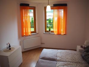 een slaapkamer met een bed en twee ramen met oranje gordijnen bij Apartament DOMINO in Karpacz