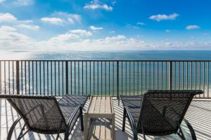 a table and chairs on a balcony with the ocean at Phoenix West 2203 in Orange Beach