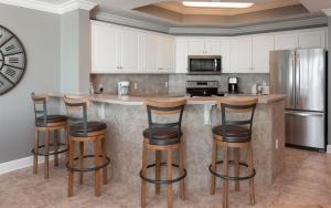 a kitchen with bar stools and a refrigerator at Phoenix West 2203 in Orange Beach