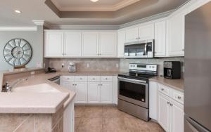 a kitchen with white cabinets and a sink and a stove at Phoenix West 2203 in Orange Beach +43 photos