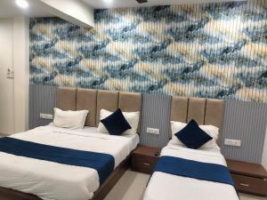 due letti in una stanza con un murale sulla parete di Hotel New Rest Inn a Mahesāna