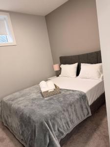a bedroom with a large bed with a gray blanket at Cozy and comfortable in Calgary