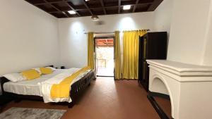 a bedroom with a bed with yellow sheets and a fireplace at Colonial canopy in Suntikoppa