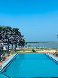 a blue swimming pool with a view of the ocean at Saachi Lagoon Resort in Kalpitiya +10 photos