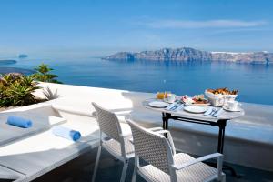 een tafel en stoelen op een balkon met uitzicht op de oceaan bij Andromeda Villas & Spa Resort in Imerovígli