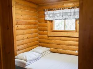a bed in a log cabin with a window at Eetuntupa in Keuruu