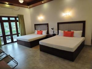 a bedroom with two beds and a window at Walker's Residency in Anuradhapura