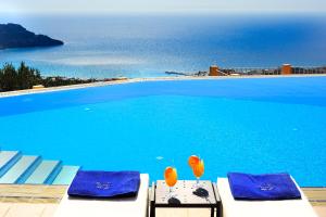 a large swimming pool with blue water and blue chairs at Stefanos Village in Myrthios