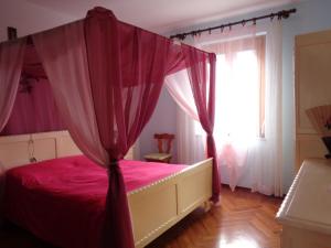 a bedroom with a pink bed with a canopy at Appartamento Fantasia CIR Aosta 0241 in Aosta