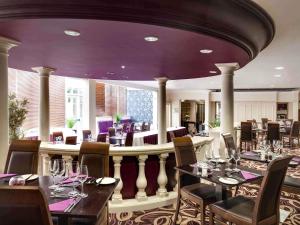 a restaurant with tables and chairs and purple ceilings at Mercure Dartford Brands Hatch Hotel & Spa in Dartford
