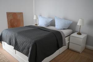 a bedroom with a bed with a black blanket and two lamps at Heimathaven 2 in Bremerhaven