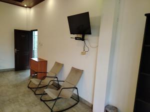 a room with four chairs and a television on a wall at Walker's Residency in Anuradhapura