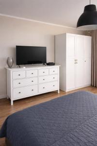 a bedroom with a white dresser with a television on it at studio Szymanowskiego 5 in Szczecin