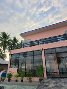 a pink building with glass windows and palm trees at โรงแรมเลทุ่งแล่น 109 in Ban Phru Ching (1) +18 photos