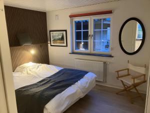 a bedroom with a bed and a mirror and a chair at Hegedal Fjordhouse in Hobro
