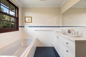 a white bathroom with two sinks and a tub at Chestnut Tree Farm in Werai +25 photos