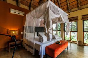 a bedroom with a canopy bed and an orange ottoman at Divava Okavango in Bagani