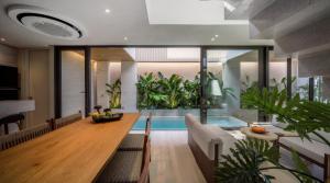 a dining room with a table and a swimming pool at POV Pool Villas in Ko Larn