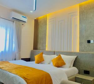 a bedroom with a bed with orange and white pillows at TGH Gracies Hotel in Port Harcourt +17 photos