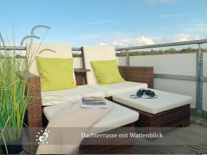 a balcony with two cushioned chairs and a book at Ferienwohnung de Lark Penthouse mit Nordseeblick in Dorum-Neufeld