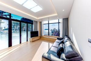 a living room with a leather couch and a television at The Bay Jeju Resort in Seogwipo