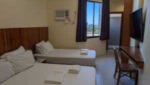a room with two beds and a desk and a window at Tsai Hotel and Residences in Cebu City