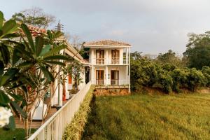 a white house with a fence in a field at ISOLA - Surf House in Ahangama