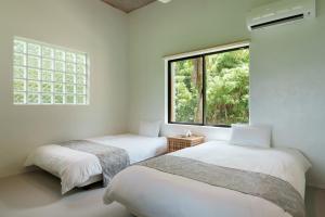 two beds in a white room with a window at Palm Hills in Ishigaki Island