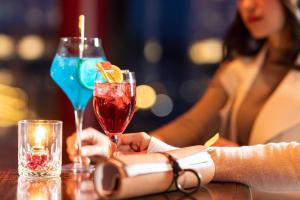 a woman sitting at a table with two cocktails at Hotel Nord Otaru in Otaru