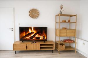 a living room with a fireplace and a clock on the wall at Emden City Center - Innenstadt in Emden